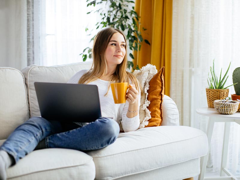 woman laying on couch and using laptop