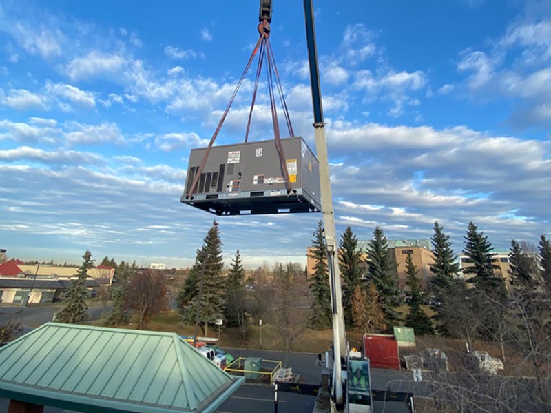 rooftop HVAC unit being lifted with crane