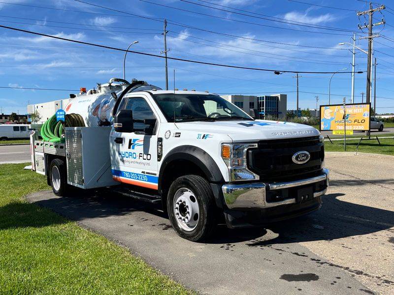 Hydro-Flo Plumbing & Heating’s white sewer truck with blue stripes, parked in Edmonton, Alberta